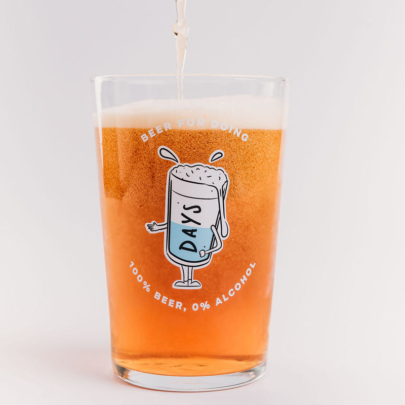 Glass of non-alcoholic beer being poured into a Day's branded pint glass.